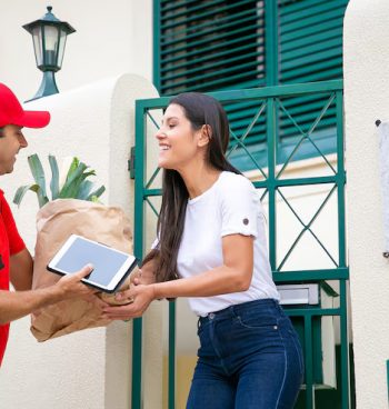 happy-woman-receiving-food-from-grocery-store-taking-package-from-courier-her-gate-shipping-delivery-service-concept_74855-11832